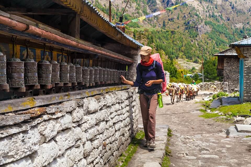 Annapurna Community trek – vrouwelijke wandelaar draait aan gebedsmolens langs de trails
