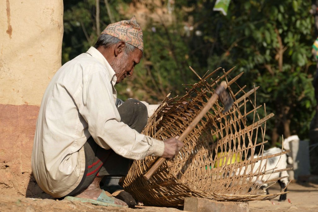 Kathmandu vallei trekking – Nepalese man met typisch Nepalees hoedje maakt een rieten mand