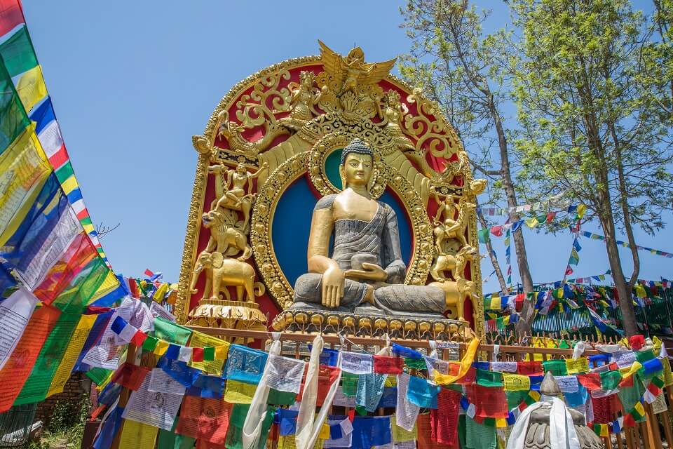 Namobuddha – beeld van Boeddha met gebedsvlagjes op het kloosterdomein