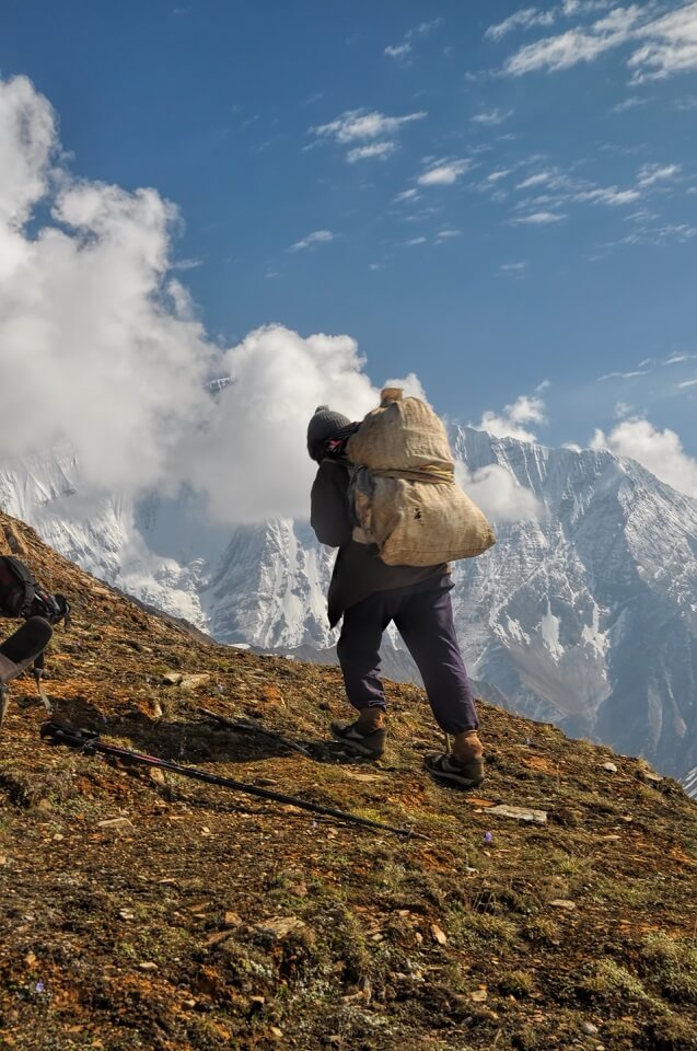 Sherpa Culture trekking – een drager draagt goederen de berg op tijdens de trekking